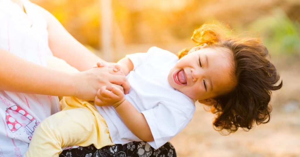 joyful child laughing on mom's knee